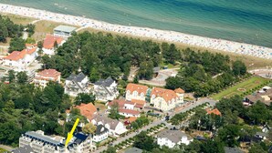 Vista aérea de un pueblo costero con playa, edificios residenciales y un parque.