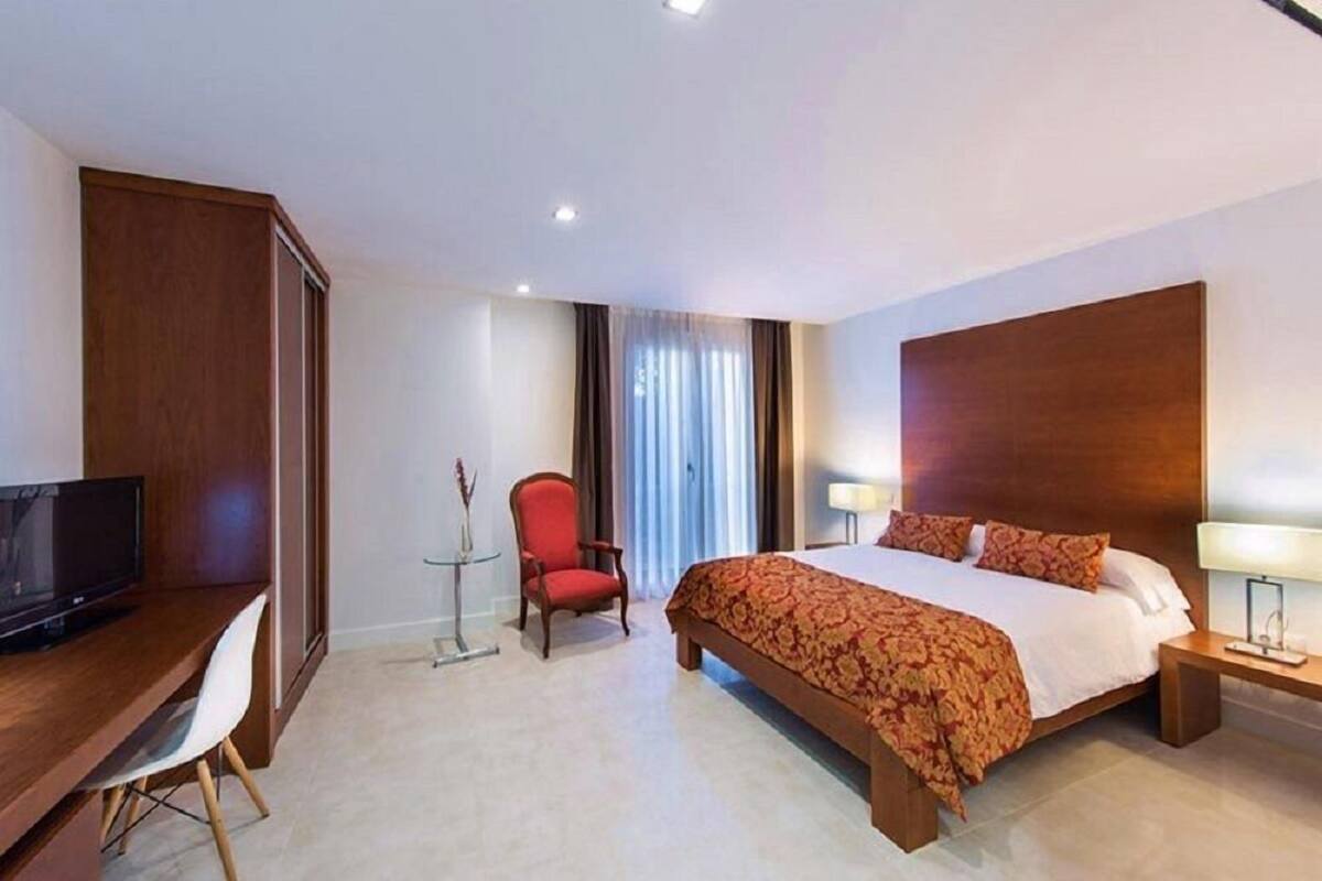 A hotel room with a bed, a desk, a TV, a chair, and a nightstand.