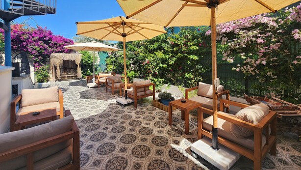 A patio area with outdoor furniture, including sofas and chairs, under large umbrellas.