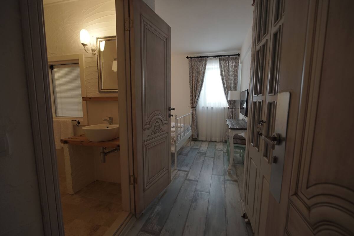 Un couloir menant à une salle de bain équipée d’un lavabo, d’un miroir et d’un luminaire.