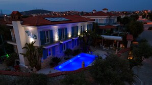 A two-story house with a swimming pool, stone facade, and red-tiled roof.