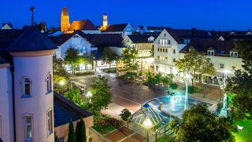 Ein Stadtplatz mit Kreisverkehr, Gebäuden im traditionellen Stil und einem Brunnen.
