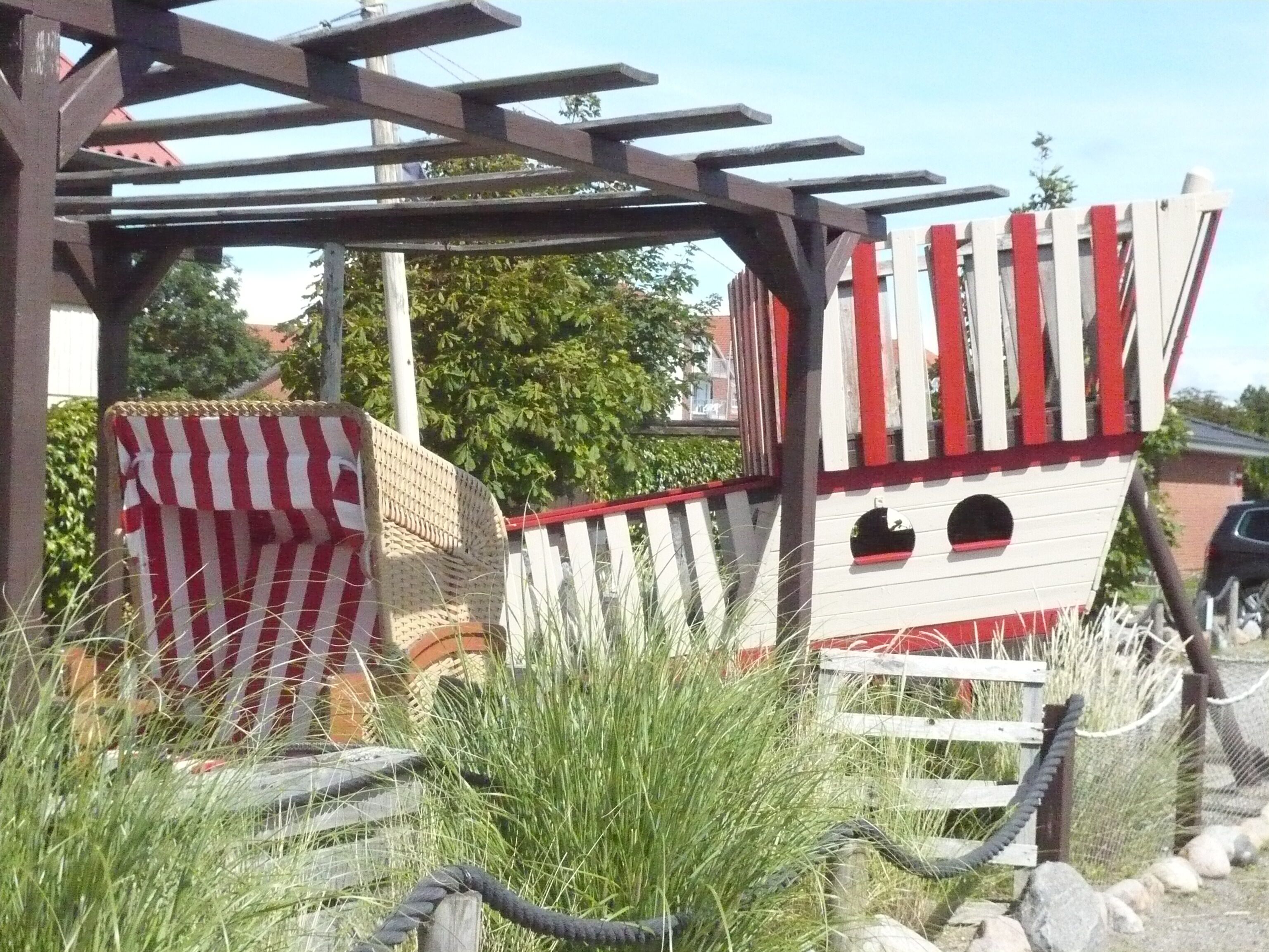 A wooden structure with a red and white striped awning and a white fence with red accents.