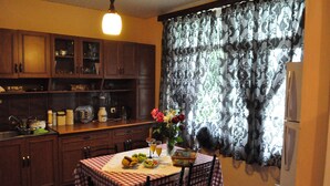 Una cocina con armarios de madera, una mesa de comedor con mantel a cuadros y un jarrón de flores.