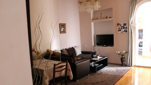Una sala de estar con sofá, televisor y una mesa de comedor con sillas.
