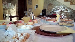 Una mesa de comedor con diversos postres y pasteles, un florero y una botella.