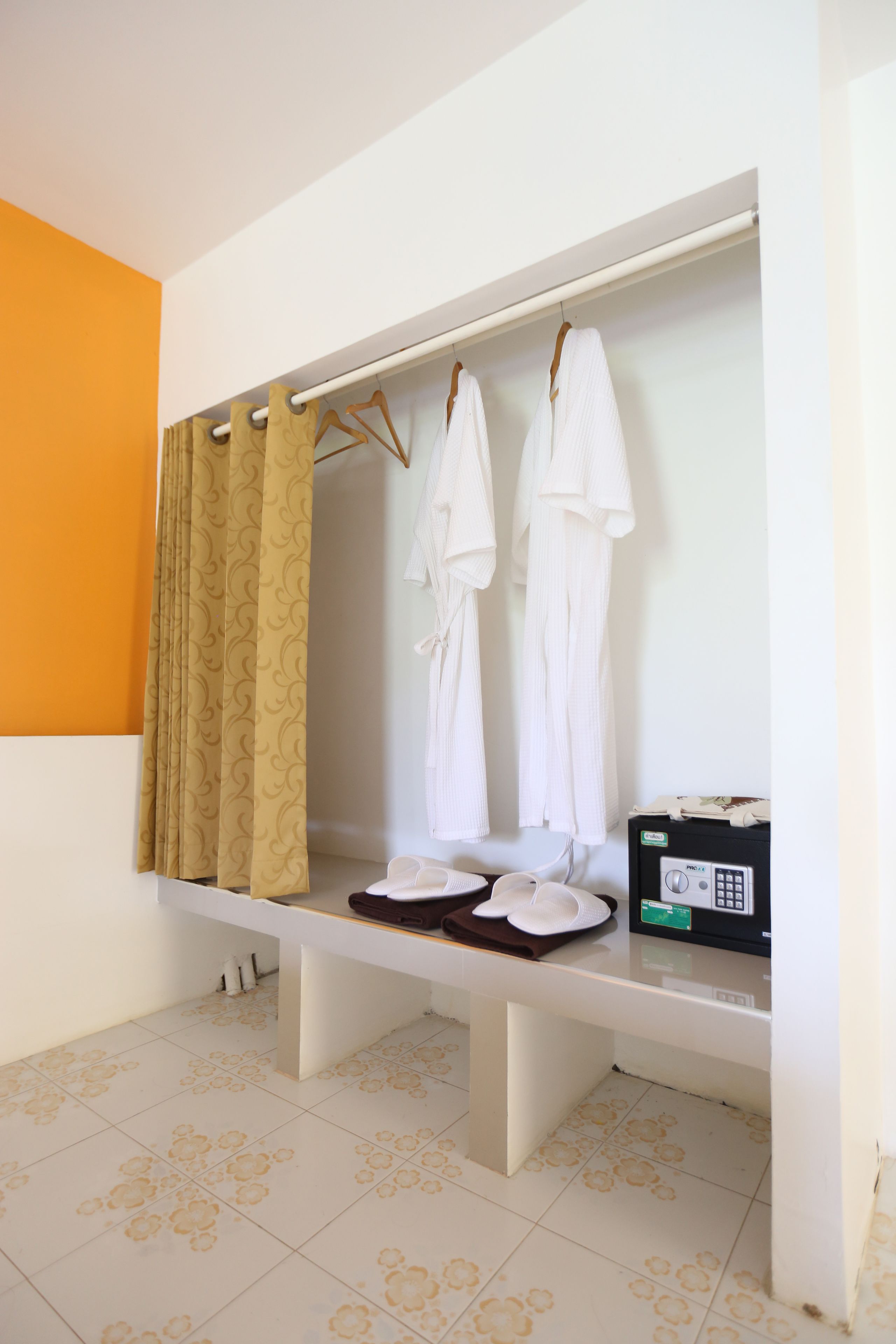 A bathroom with a shower area, a bench, and a towel rack with white towels.