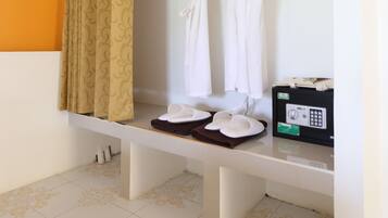 A bathroom with a shower area, a bench, and a towel rack with white towels.