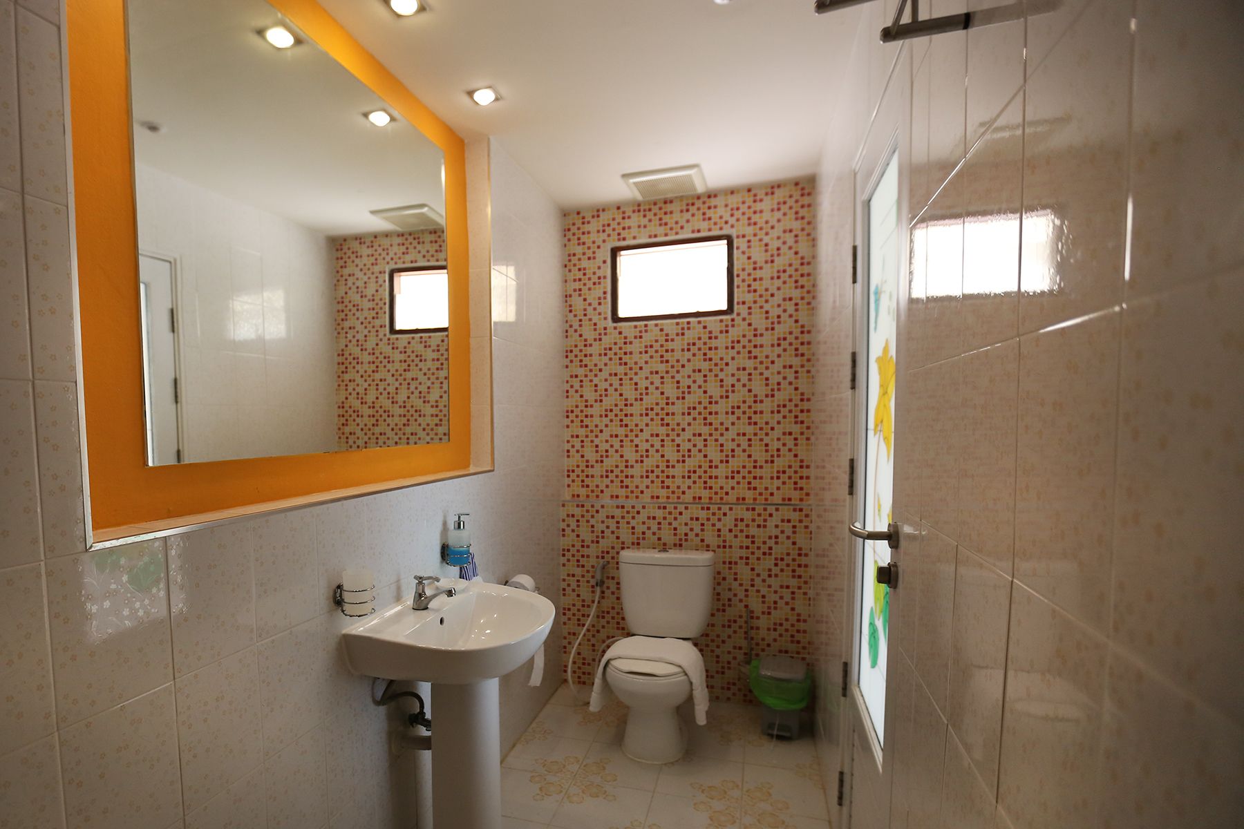 Un baño con lavamanos, inodoro y espejo.