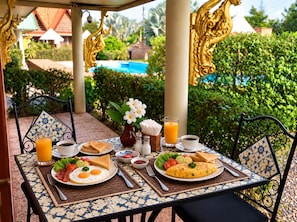 A table set for breakfast with a view of a pool and greenery. - The Orchid Resort & Relax (Kantharawichai)