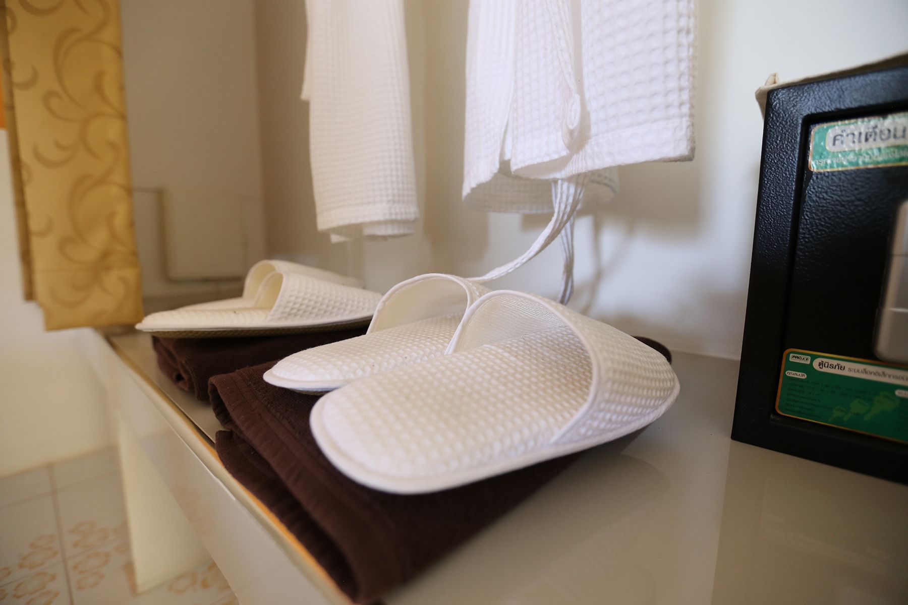 Un par de pantuflas blancas sobre una toalla marrón en un baño.