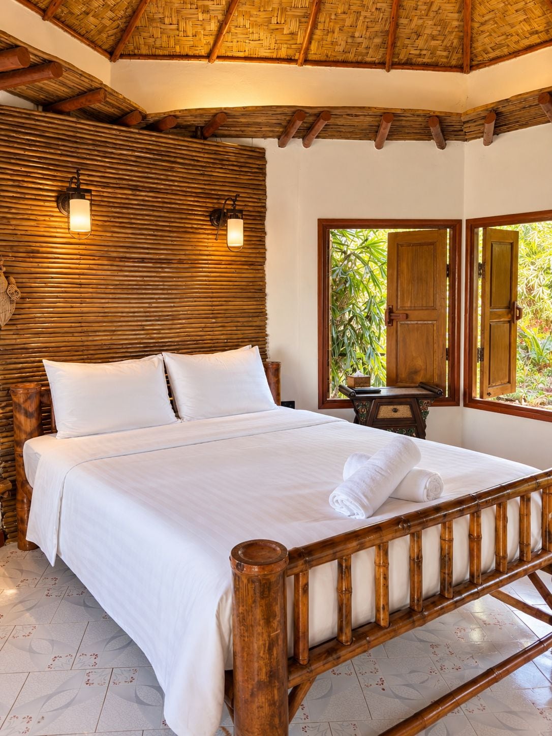Una cama con ropa blanca, cabecera de madera y mesita de noche con lámpara.