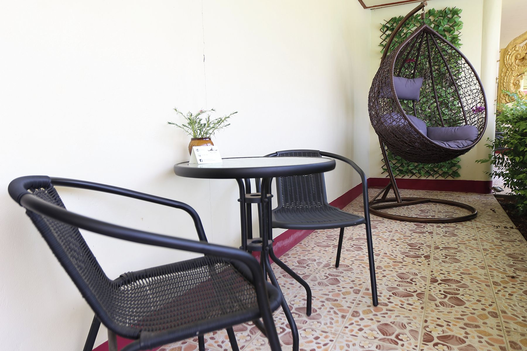 A small outdoor seating area with two chairs and a table, a hanging chair, and a potted plant.