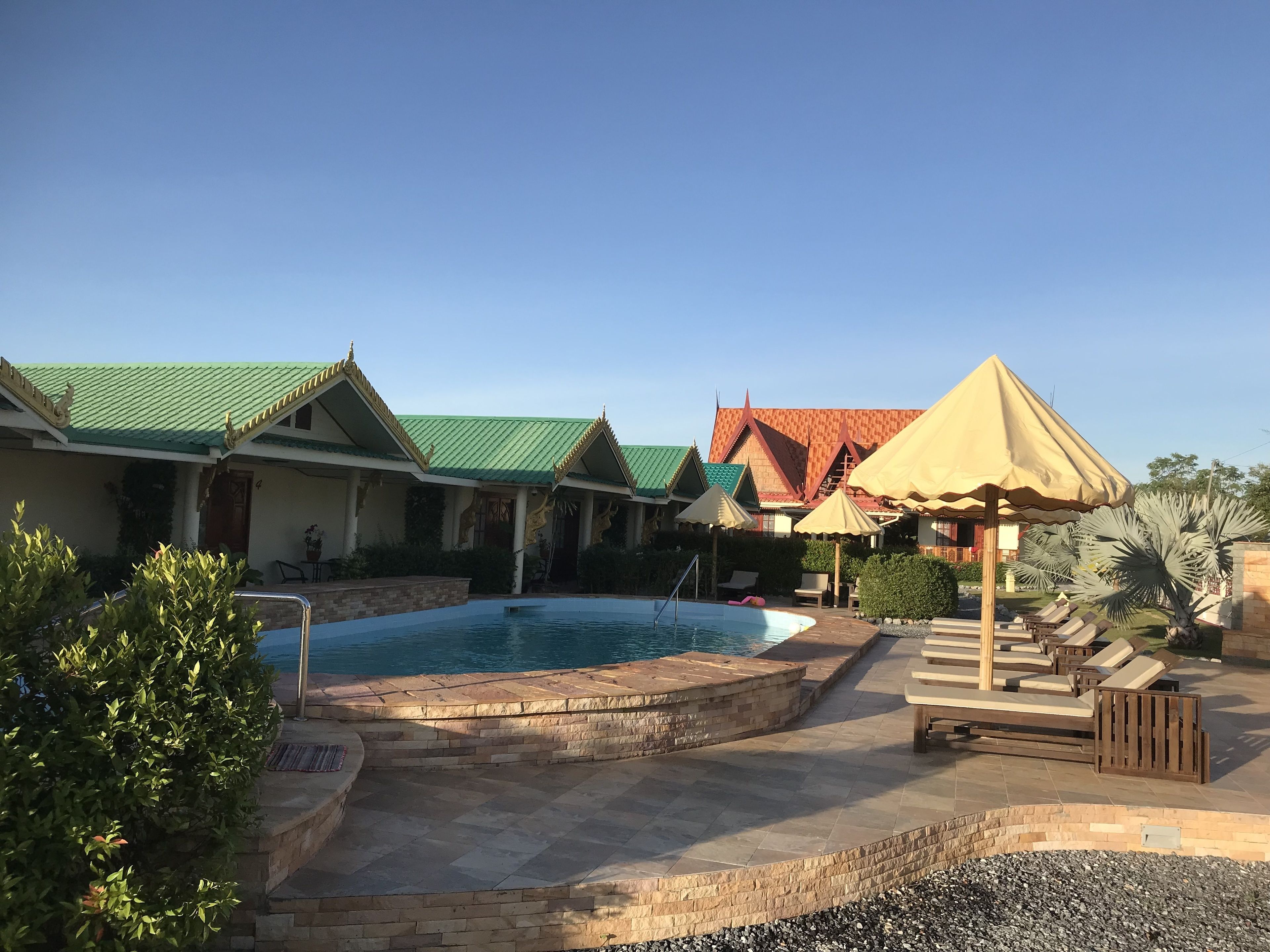 A swimming pool area with a pool, lounge chairs, and umbrellas.