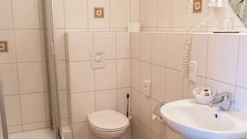 Ein Badezimmer mit Dusche, Toilette, Waschbecken und Mülleimer.