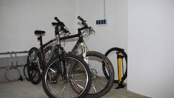 Una bicicleta con una botella de agua y un inflador apoyada contra una pared en una habitación con suelo de baldosas.