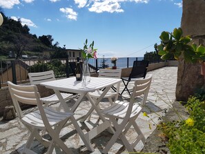 A terrace with a table and chairs, a bottle of wine, and a vase with flowers. - Augusto charming flat with sea view (Monterosso al Mare)