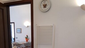 A dining area with a table set for four, a bowl of fruit, and a clock on the wall. - Augusto charming flat with sea view (Monterosso al Mare)
