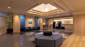 A modern lobby with a seating area, a reception desk, and a large digital kiosk. - Keikyu EX Inn Shinagawa Shimbamba (Tokyo)