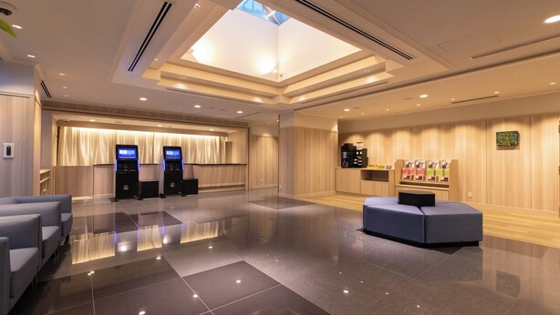 A modern hotel lobby with a reception desk, seating area, and vending machines. - Keikyu EX Inn Shinagawa Shimbamba (Tokyo)