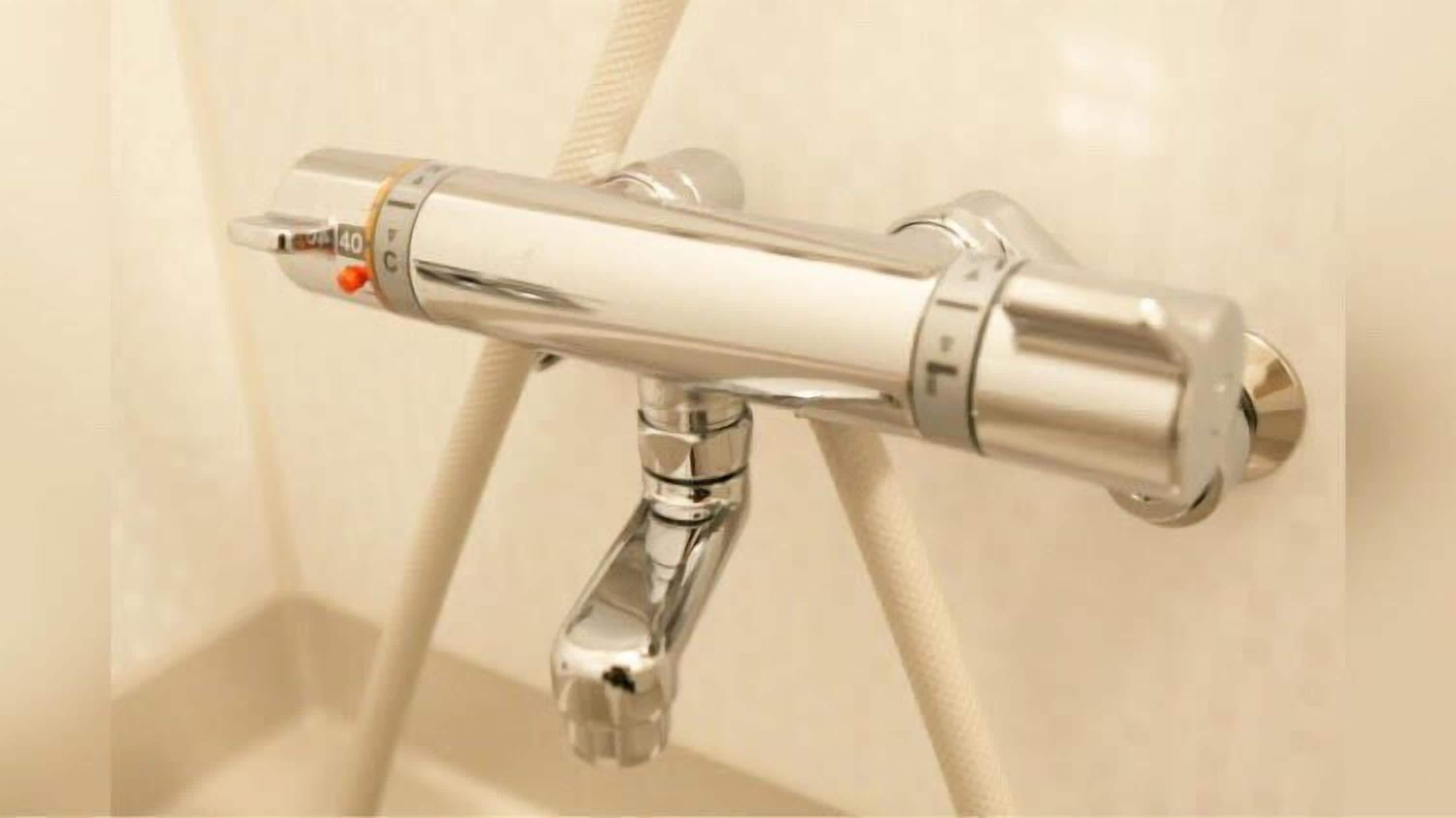 A chrome faucet with a temperature control knob and a flexible hose attached to it.