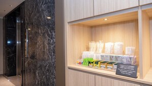 A hotel reception area with a marble wall and a display case containing toiletries and snacks. - Keikyu EX Inn Shinagawa Shimbamba (Tokyo)