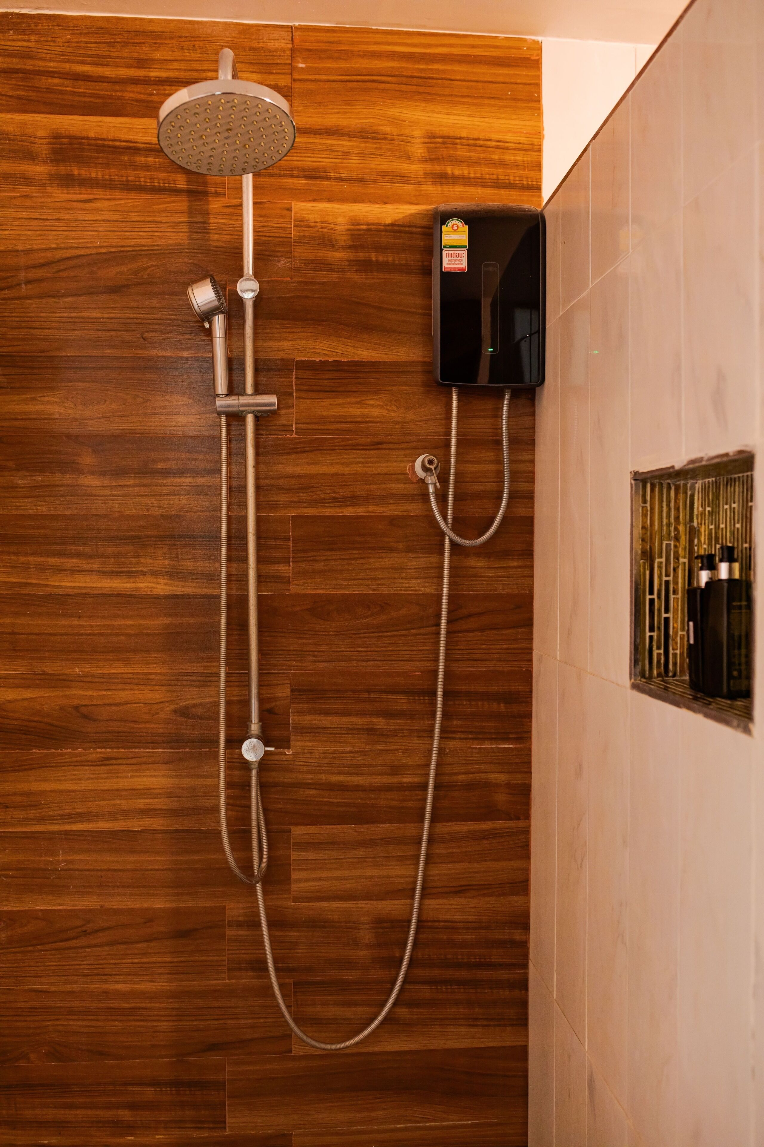 A shower with a handheld showerhead and a wall-mounted control panel.