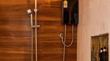 A shower with a handheld showerhead and a wall-mounted control panel.