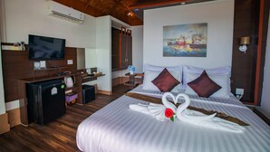 A hotel room with a bed, a TV, a desk with a computer, and a painting on the wall. - Chareena Hill Resort - Pattaya Beach Koh Lipe (Koh Lipe)