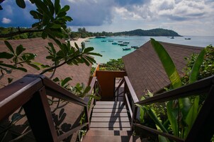 A staircase leading to a beach with boats in the water and a view of the coastline.