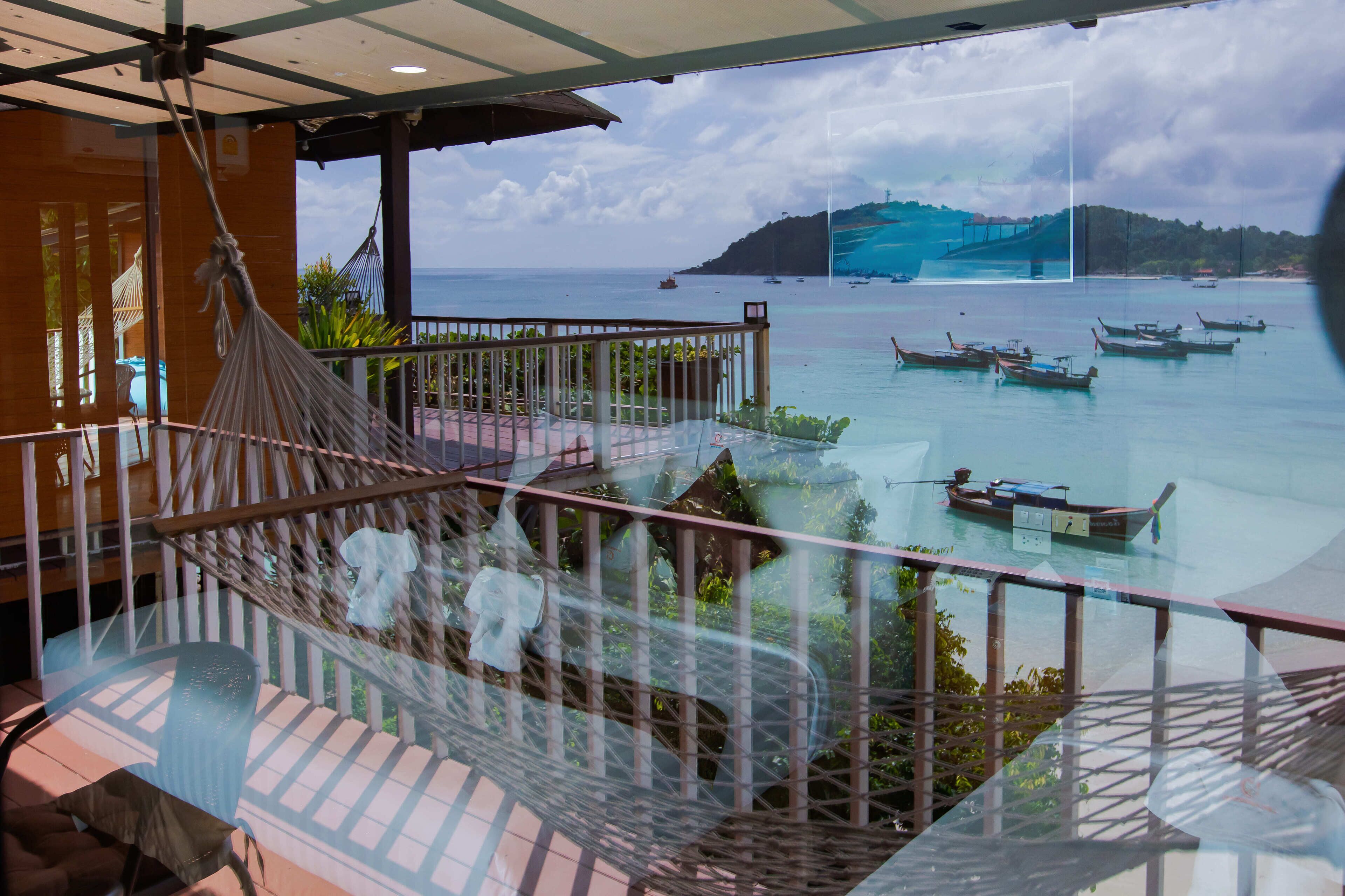A hammock on a balcony with a view of boats on the water.