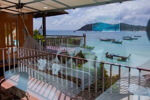 A hammock on a balcony with a view of boats on the water.