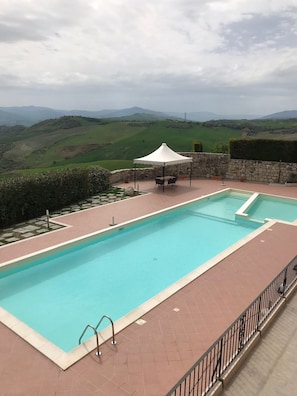 Een buitenzwembad, ligstoelen bij het zwembad