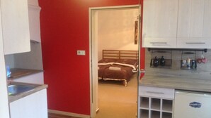 Een knus verblijf met een kitchenette, een bed en een kleine badkamer.
