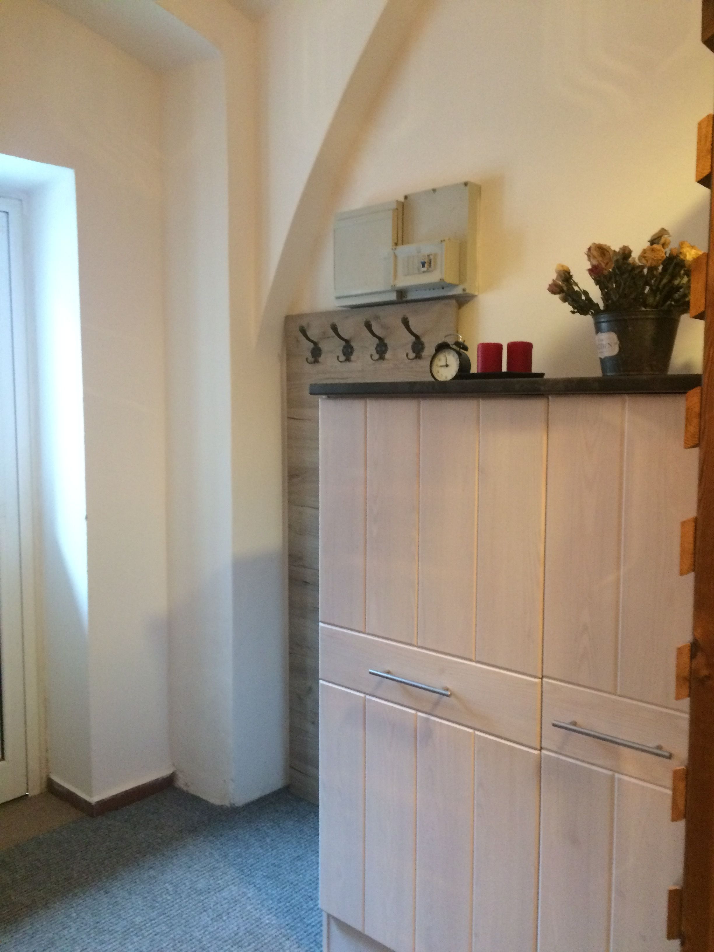 Un coin de pièce avec une armoire en bois, une horloge et une petite plante en pot.