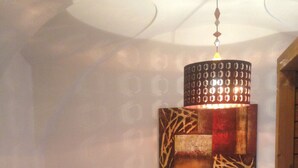 Een slaapkamer met een bed, een bijzetbed, een hanglamp en een kunstwerk aan de muur.