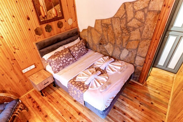 Una habitación de madera con una cama, una mesita de noche de madera y una pared de piedra.