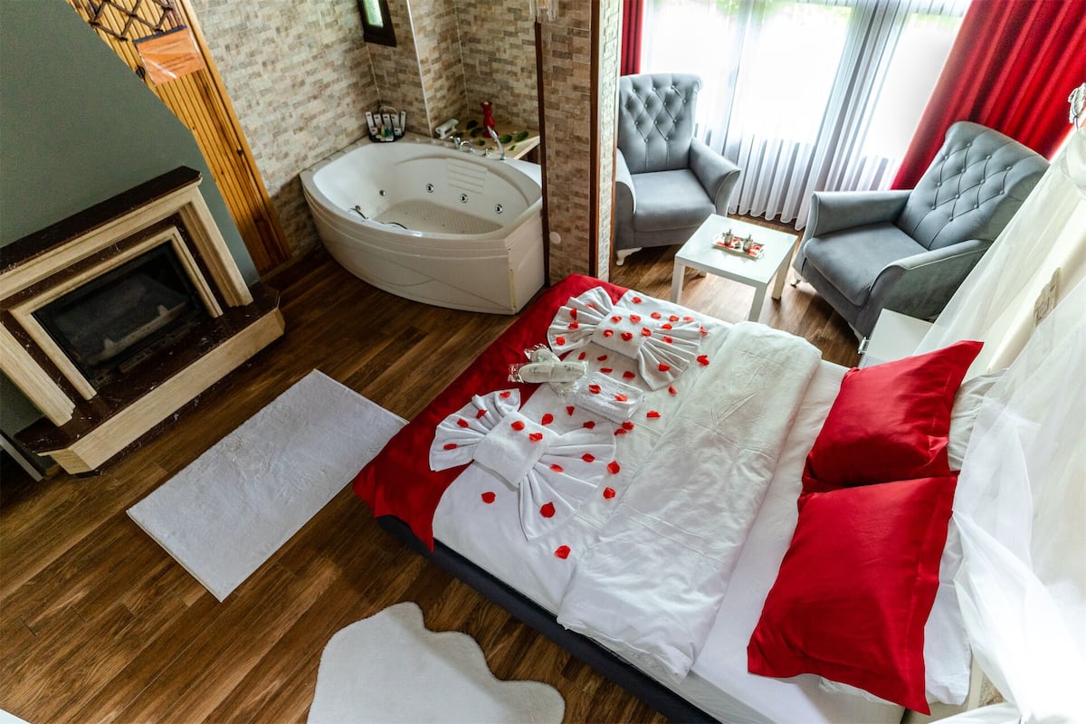 Una habitación de hotel con una bañera grande, un sofá, una silla y una mesita.