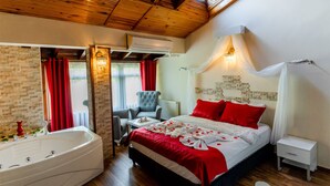 Una habitación de hotel con una cama grande, una zona de estar con una silla, una bañera y una mesita.