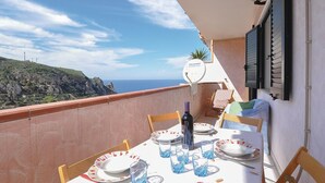 A balcony with a table set for two, overlooking a coastal landscape. - Amazing apartment in Buggerru with house sea view (Buggerru)