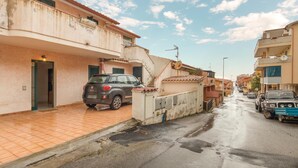 A residential street with houses, a parked car, and a satellite dish. - Amazing apartment in Buggerru with house sea view (Buggerru)
