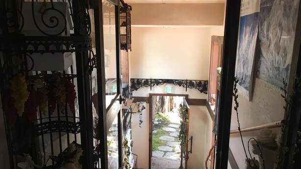 Vista de un pasillo que conduce a una habitación con piso de baldosas y una puerta con letrero de salida verde.