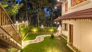 Un espacio exterior bien iluminado con un sendero sinuoso, una escalera y un edificio de arquitectura tradicional y un mural.