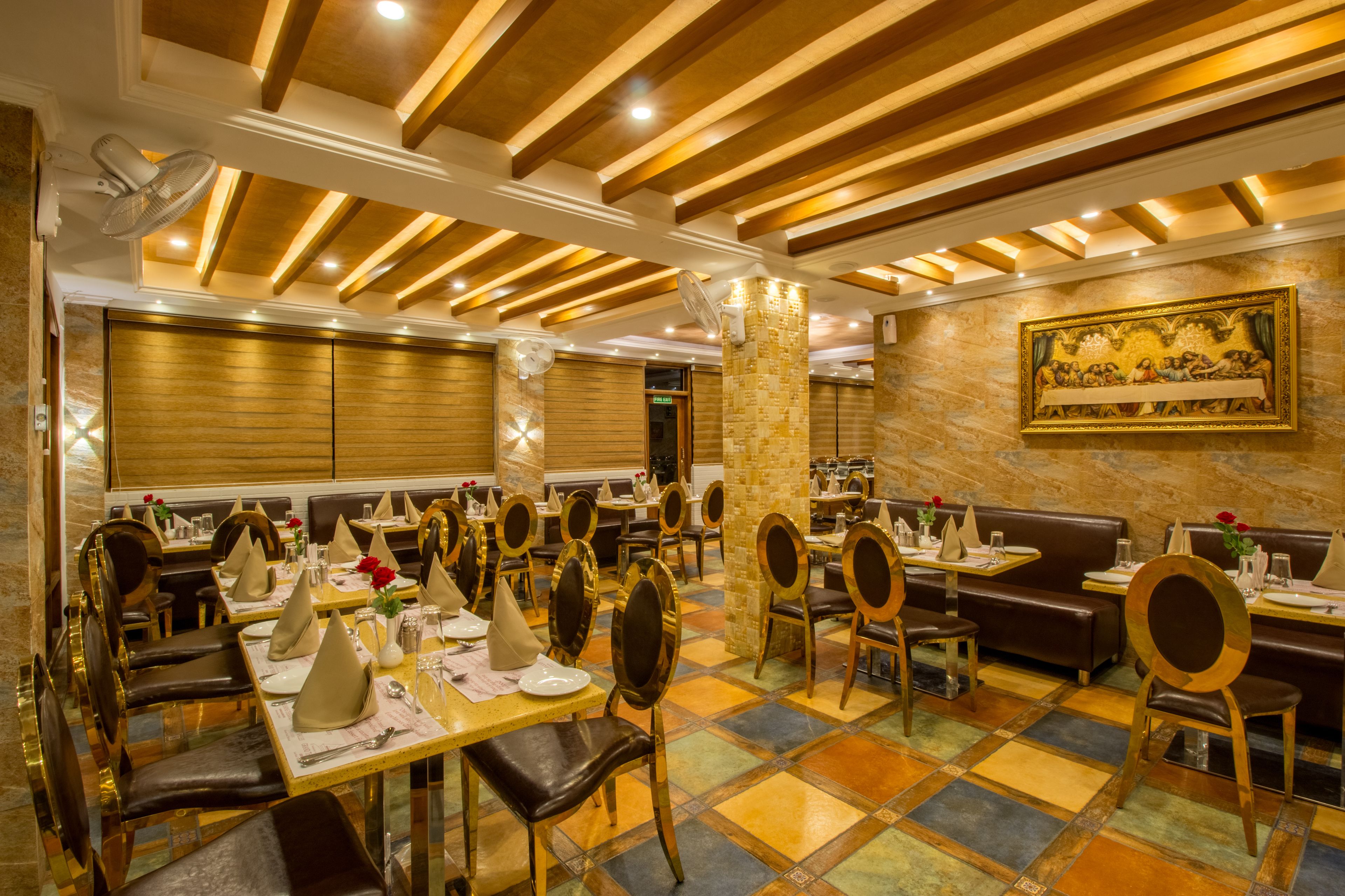 Un restaurant doté de nombreuses tables et de plusieurs coins repas, chaque table étant dressée avec des assiettes, des couverts et des serviettes.
