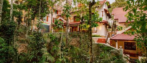 A hotel with multiple floors, surrounded by lush greenery.