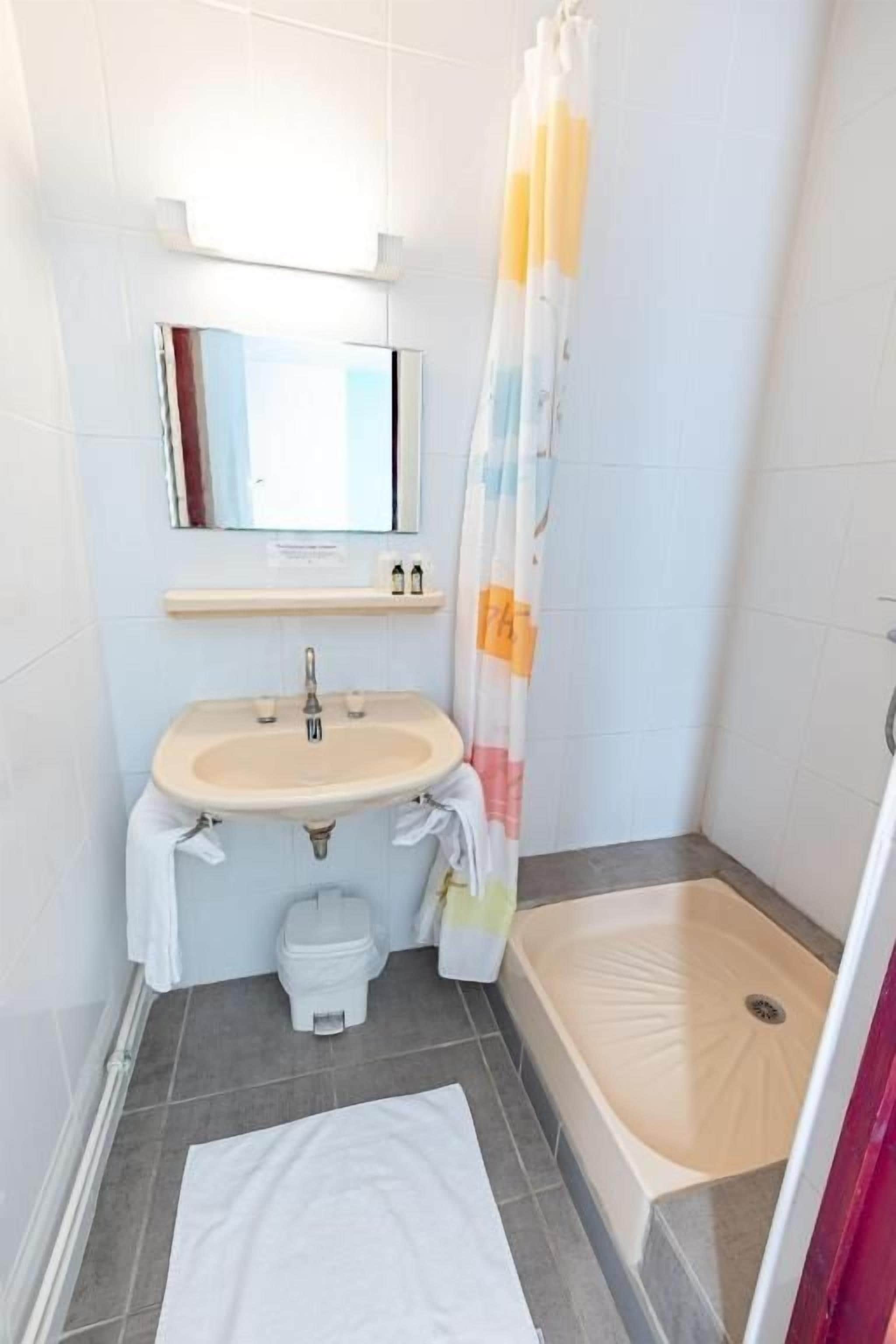A bathroom with a sink, toilet, and shower area.