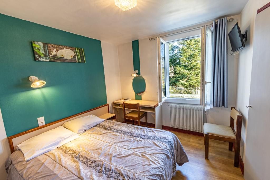 Un dormitorio con cama, escritorio, silla y ventana con vistas a zonas verdes.