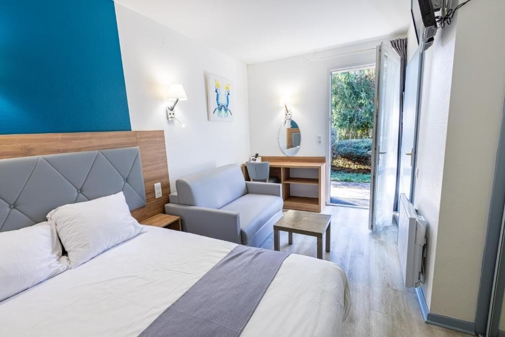 Una habitació d'hotel amb un llit, un sofà, un escriptori i vista a l'exterior.