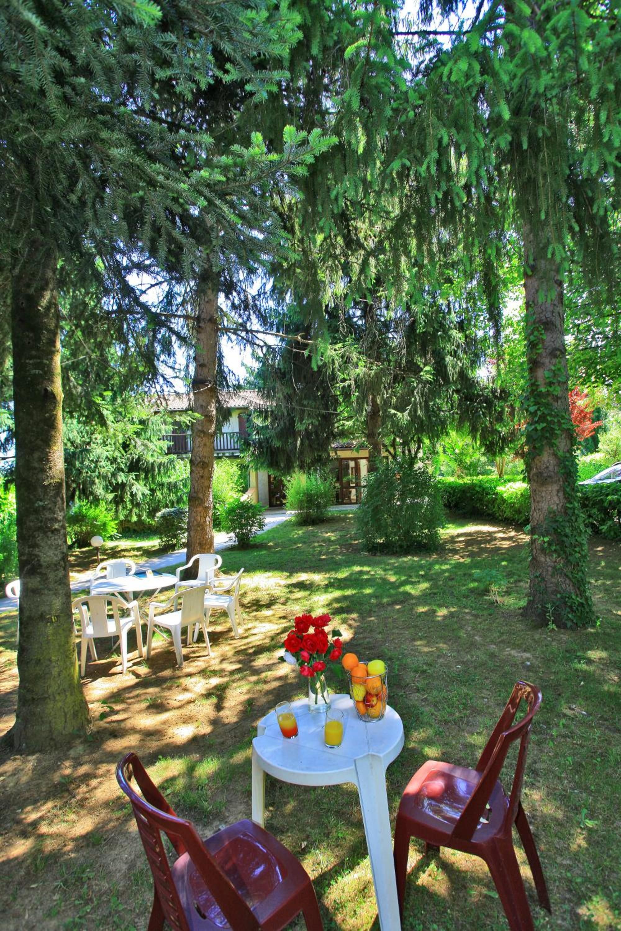 An outdoor seating area with a table set for two, surrounded by greenery and trees.