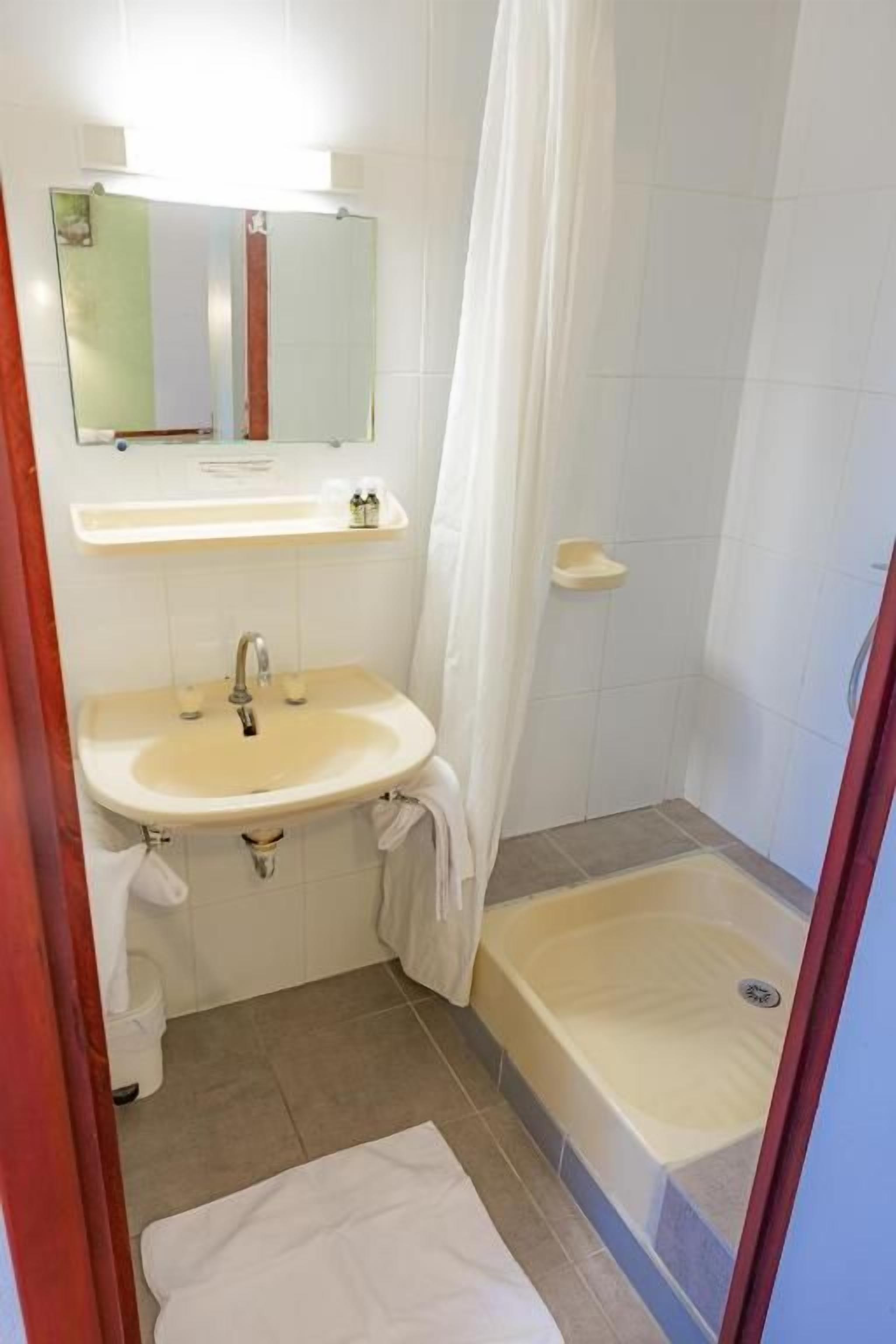 Ein Badezimmer mit Waschbecken, Spiegel und Duschbereich.
